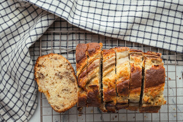 Wall Mural - Fresh banana bread on the white background. Homemade pastry on the checkered cloth. Flat lay