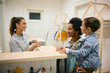 © Drazen - Happy black mother and her son talk to a teacher at reception desk at daycare.