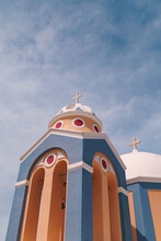 Blue And Orange Church Building In Santorini, Greek Island. Blue Sky With Fluffy Light White Clouds.