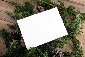 Wall Mural - Christmas 7x5 card mockup template on natural fir twigs on wooden background. Design element for Christmas and New Year congratulation, rsvp, thank you, greeting or invitation card, sale