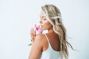 Wall Mural - Beauty portrait of blonde hair young woman with pink peony in hand isolated on white background