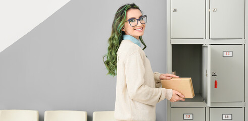 Canvas Print - Beautiful female student with book near locker at the university