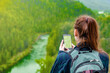 Young woman uses smartphone at mountains and using travel app or map during her hike. Empty space for text
