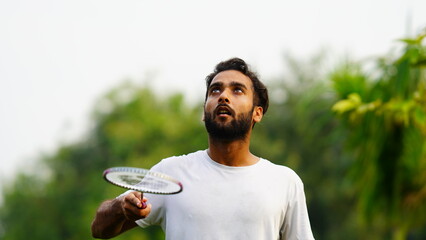 man playing badminton racket with shuttlecock in park