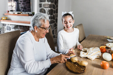 Wall Mural - Hispanic grandmother and granddaughter cooking at home  in Mexico Latin America