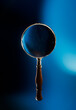 Vintage magnifying glass on a blue background with dramatic lighting. 3D rendering, illustration.