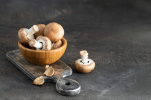 Uncooked Portobello Mushrooms In Wooden Bowl On Cut Board Ingredient Background With Copy Space