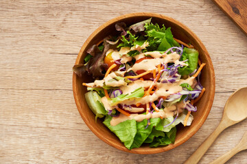 Wall Mural - top view or flat lay mix salad from green leaves and cherry tomato in a wooden bowl with a spoon and fork on white wood table background. copy space                          