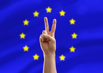 politics and gesture concept - close up of male hand showing peace over flag of european union on background