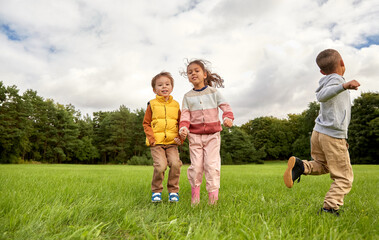 Wall Mural - childhood, leisure and people concept - group of happy children playing and jumping at park