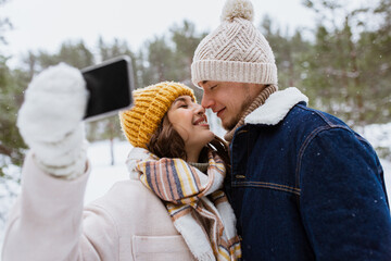 Canvas Print - season, technology and leisure concept - happy couple with smartphone taking selfie in winter park