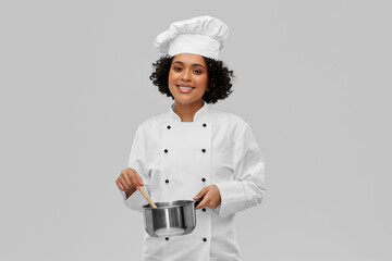 Wall Mural - culinary and people concept - happy smiling female chef in toque with saucepan cooking food over grey background