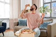 © Syda Productions - food delivery, consumption and people concept - happy man eating takeaway pizza at home