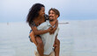 Young smiling heterosexual multiethnic couple having fun on the beach. Lovers, honeymoon