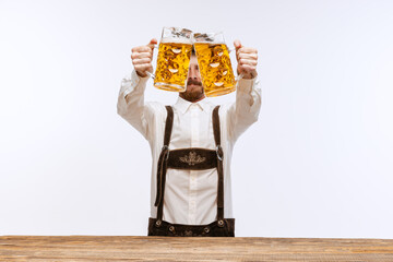 Wall Mural - Portrait of Oktoberfest young emotional man in hat, wearing the traditional Bavarian clothes, holding beer mug. Alcohol, traditions, holidays, festival concept.