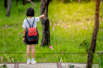 Wall Mural - Children travel in flower field and holding binoculars on green nature background