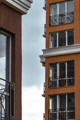 Two houses with windows opposite each other. A yellow multi-storey building against a blue cloudy sky. Street photography.