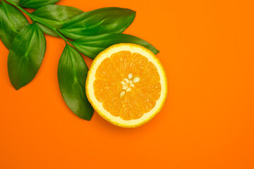 Wall Mural - Ripe juicy orange and green leaves on bright orange background. Orange fruit, citrus minimal concept. Creative summer food minimalistic background.