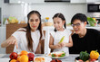 © atitaph - A happy Asian family spends lunch, vegetables, fruit, and dates at the table in their home. Cute little daughter having fun talking. Father, mother
