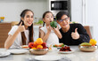 © atitaph - A happy Asian family spends lunch, vegetables, fruit, and dates at the table in their home. Cute little daughter having fun talking. Father, mother