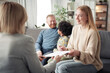 © AnnaStills - Happy young woman signing contract about adoption while talking to social worker with her family in background