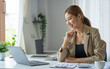 © crizzystudio - Young beautiful Asian woman working with a laptop while sitting at office desk, working from home concept.