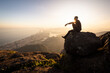 © Cavan Images - Man enjoying beautiful sunset view to city from rocky mountain top