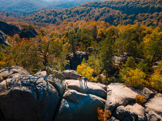 Poster - couple traveler sitting on the top of the rock with beautiful landscape of autumn forest