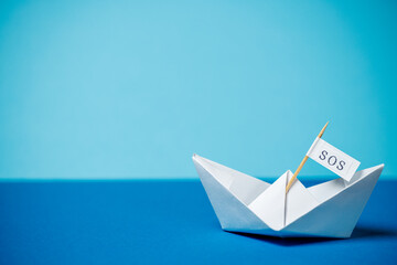 Wall Mural - sos paper boat on blue background