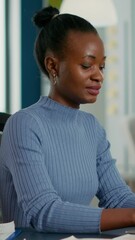 Poster - portrait of african american woman typing using laptop keyboard and smiling at camera sitting at des