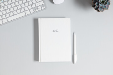 Gray office desk mockup, white book mockup, diary for 2022,, computer keyboard, plant. Flat lay, top view, copy space