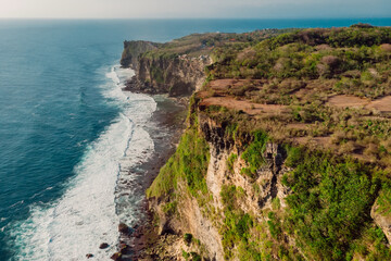 Aerial view of scenic coastline with cliffs and ocean with waves in Uluwatu, Bali