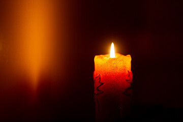 Wall Mural - burning candle in dark with glow on wall