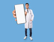 © Prostock-studio - Telemedicine. Young Male Doctor In Uniform Showing Big Blank Smartphone In Hand