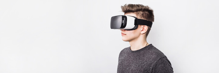 a young guy, a teenager stands in a villard vr glasses on a white background. augmented reality in o