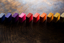 Colored Wooden Blocks Aligned On Old Vintage Wooden Table, With Light Coming Through And Dark Shadows. For Something With Concept Of Variations Or Diversity. Shallow Depth Of Field.