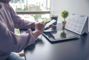 Close up Woman Hands Using Smartphone Shopping online at office desk. Woman touch screen holding smartphone open website social. Online Shopping Website on Laptop. Easy Website Shop by cellphone