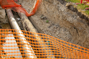 Repair of the heating plant system with the laying of new underground metal pipes in the trench. Reconstruction of the city heating system. Mesh fencing for work safety