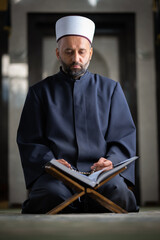 Religious Muslim man praying inside the mosque reading a Quran.