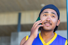 Young Male With Cap On Backwards Talking On Mobile Phone