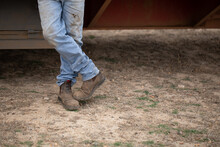 Crossed Legs Of Man Standing Wearing Dirty Jeans And Work Boots