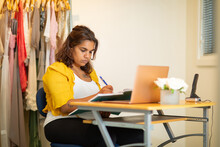 Young Woman Sitting At Small Desk With Laptop And Diary