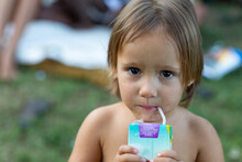 little girl with grubby face drinking from juice box