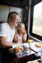 Father and daughter eating breakfast on train