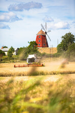 Combine Harvester And Windmill On Farm