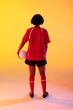 Rear view of african american female rugby player with rugby ball over neon yellow lighting