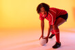 © vectorfusionart - African american female rugby player with rugby ball over neon yellow lighting