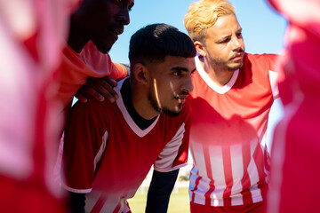 Poster - Multiracial male soccer athletes discussing while huddling in playground during match in summer