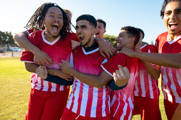 Poster - Multiracial male team players screaming while celebrating victory after soccer match at playground