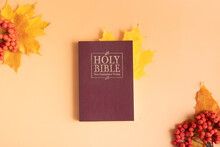 Holy Bible With Autumn Yellow Leaf On Orange Background Top View